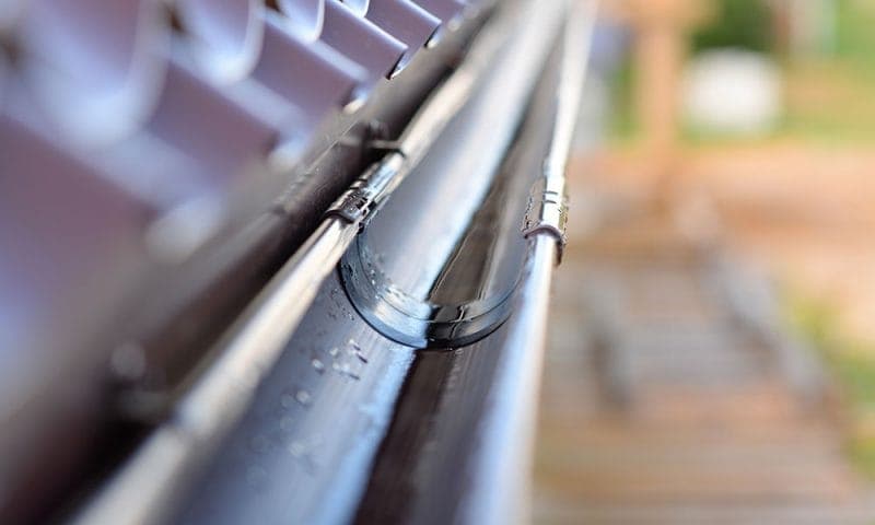 Close-up of a black gutter bracket and joint of the kind checked during a maintenance visit