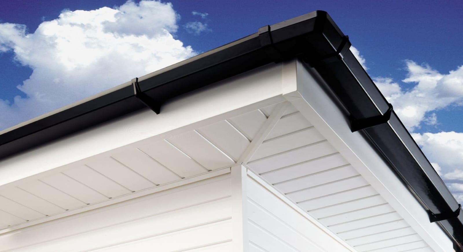 New black uPVC fascia, white soffit and black guttering fitted to the corner of a house