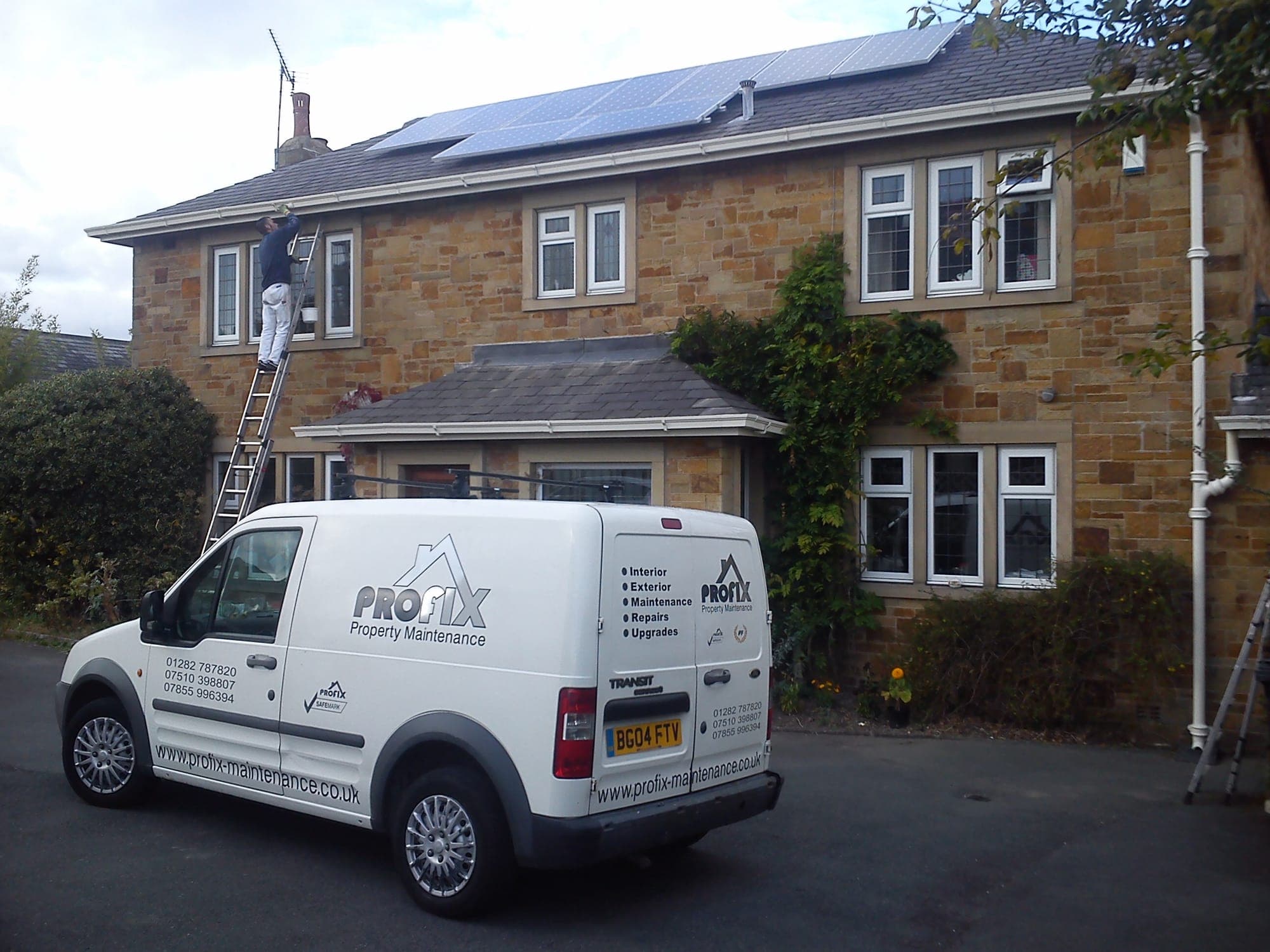 Profix Guttering technician working on the guttering of a Lancashire stone house from a ladder, with the company van parked below